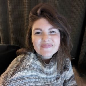 Emily Van Laan smiles wearing a striped gray sweater. 