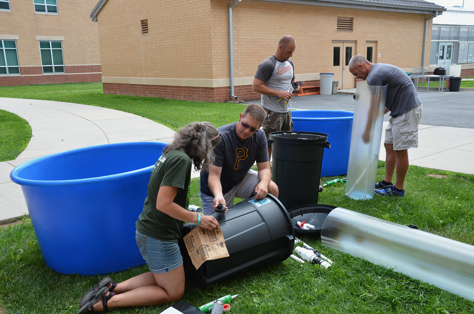 Outside a school, teachers use tubs and other materials to build aquaponics system