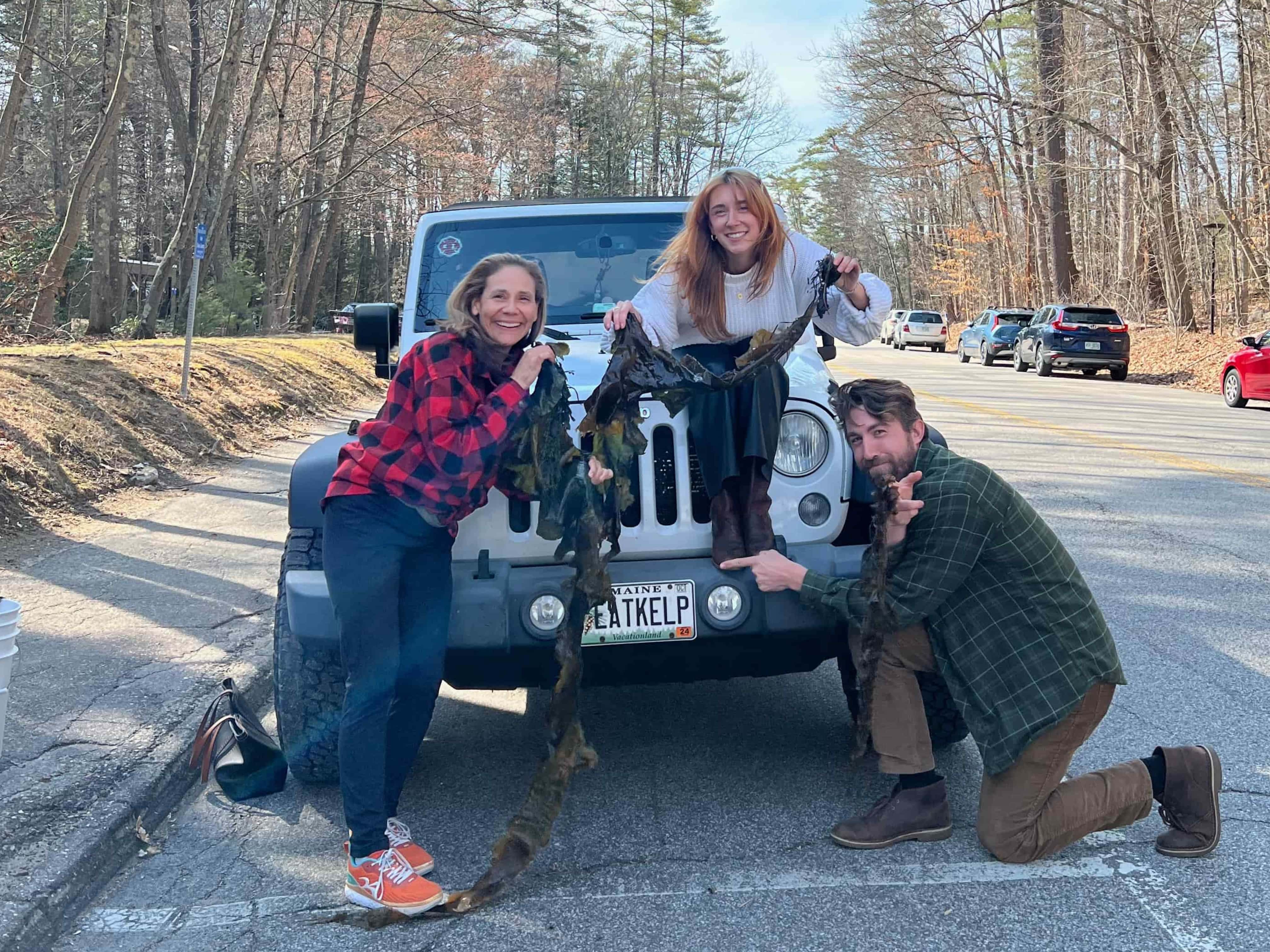 Three people holding up kelp