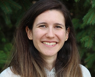 Ana Leirner smiles in front of a leavf backdrop