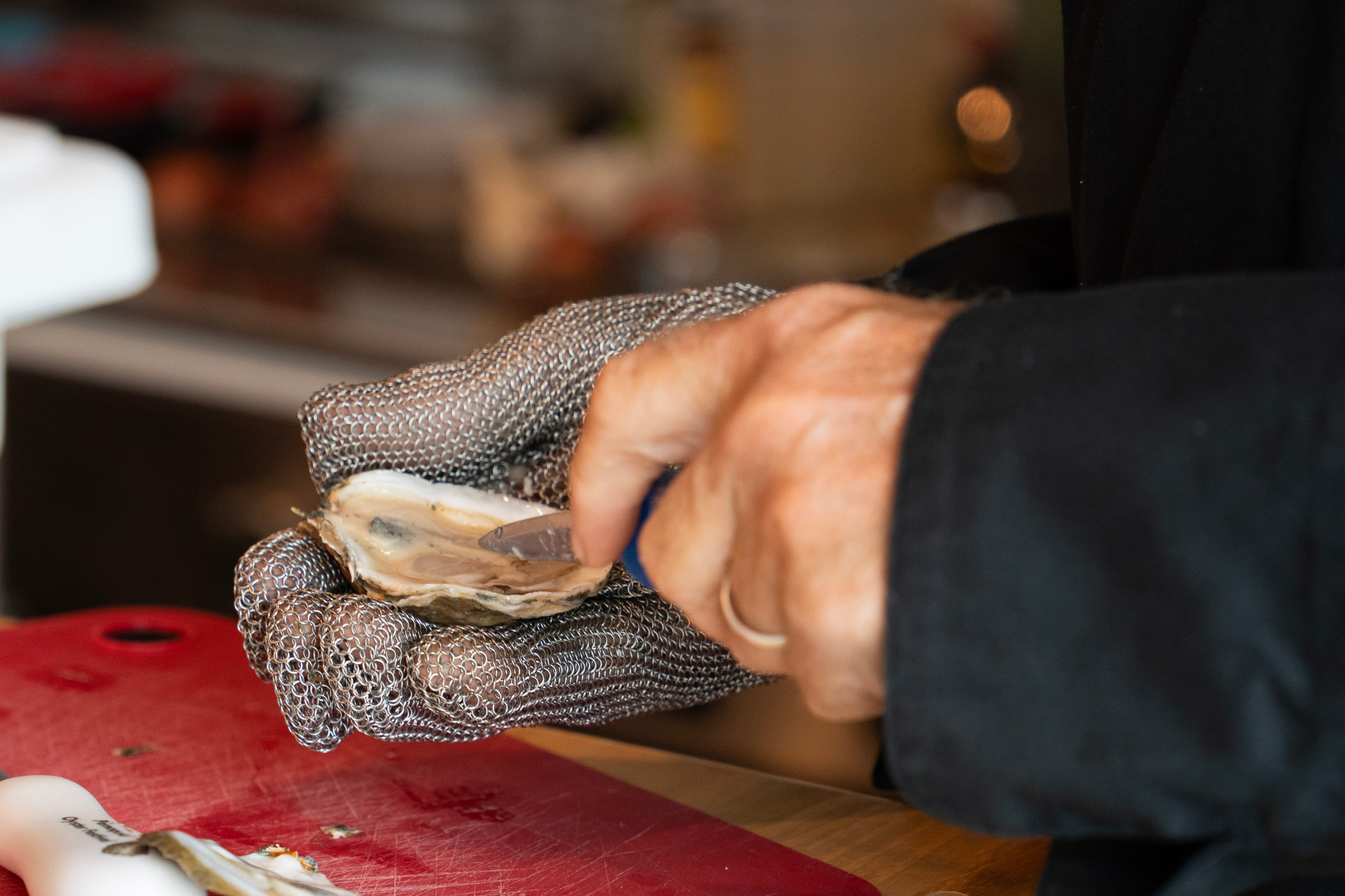 Pair of hands shuck an oyster