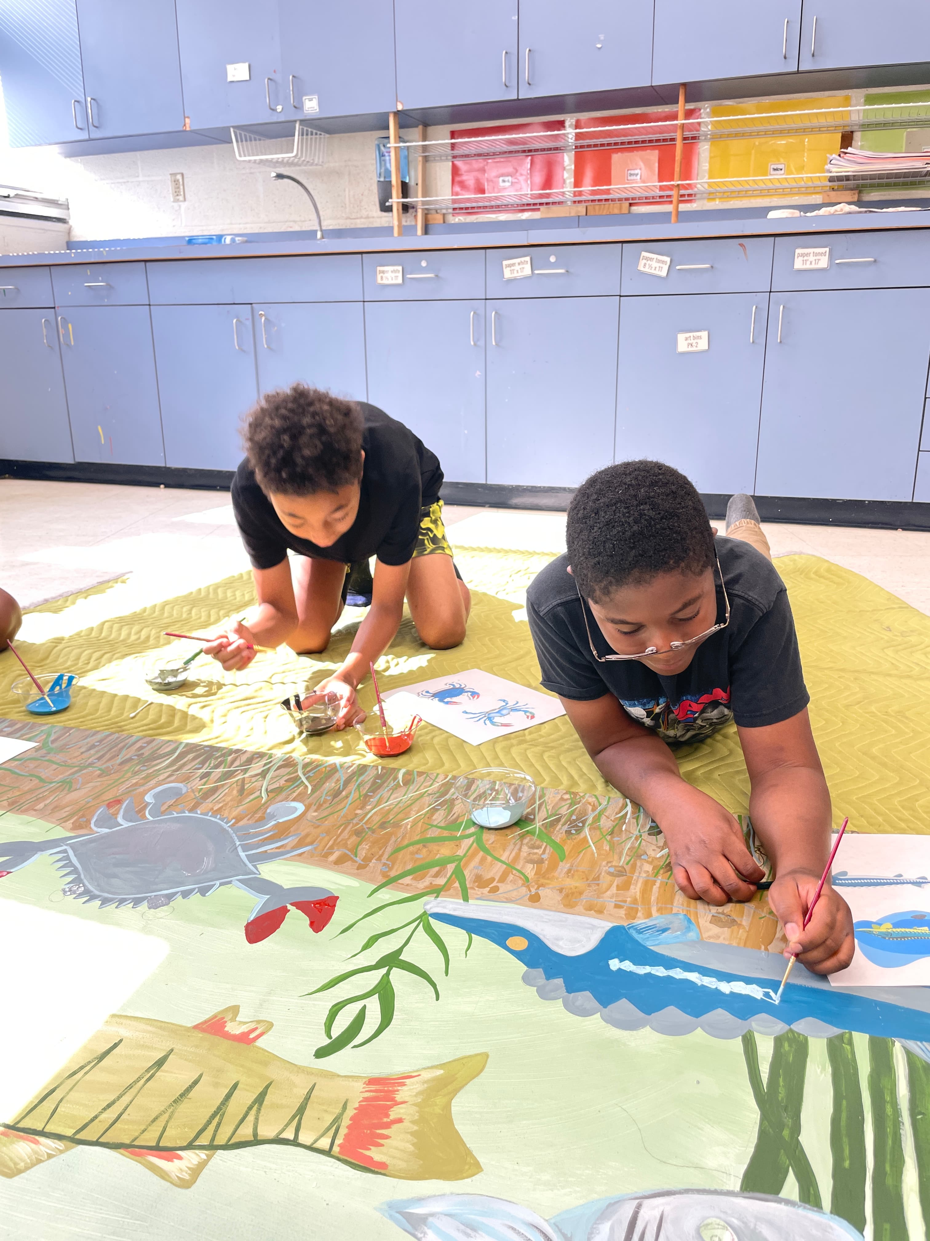 Two campers paint watershed scenes into a mural