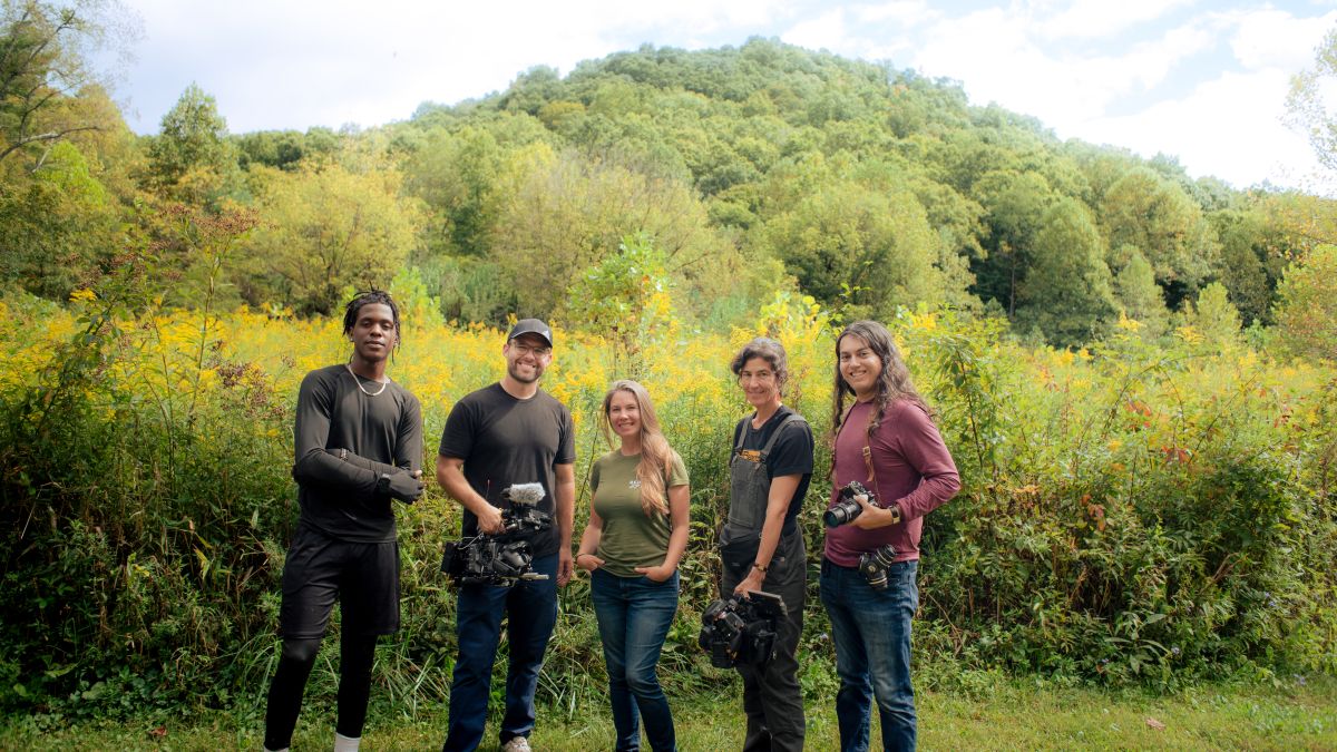 James, Juliet, and participants in In Our Nature stand near a field