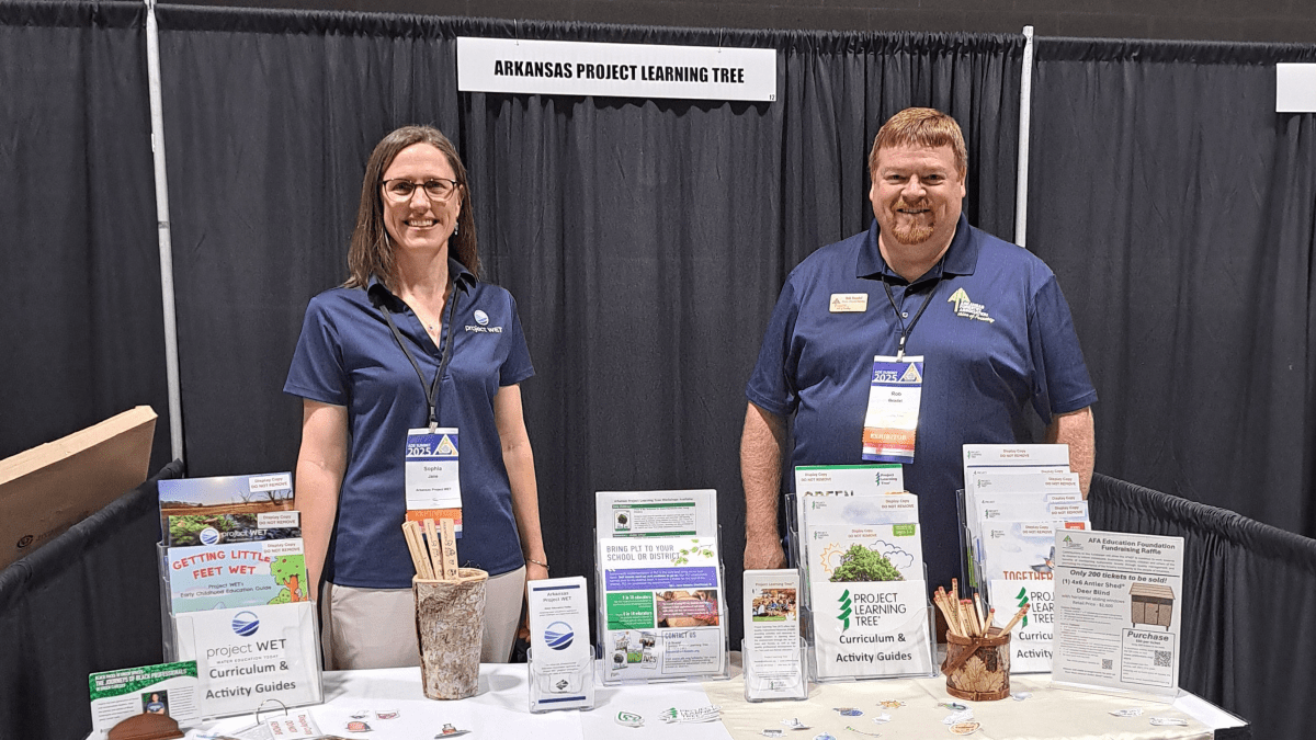 Two people stand behind a table in an exhibit booth