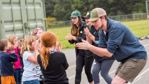 Three college students leading elementary students in an activity