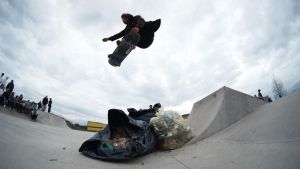 Skateboarder jumping a bag of trash. 