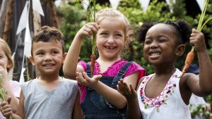 Group of kids holding carrots and on a field trip