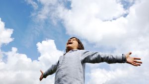 Young student reaching out and looking at sky