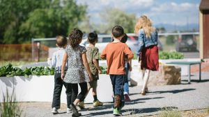 group of students following their teacher outside towards a school garden