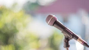 Microphone in a stand over a blurred background of green trees