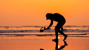 A young and independent filmmaker filming near beach silhouette