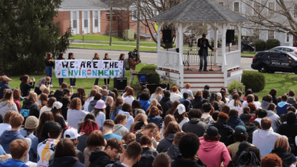 a group of people gathered in front of a speaker and a sign that reads We Are The Environment