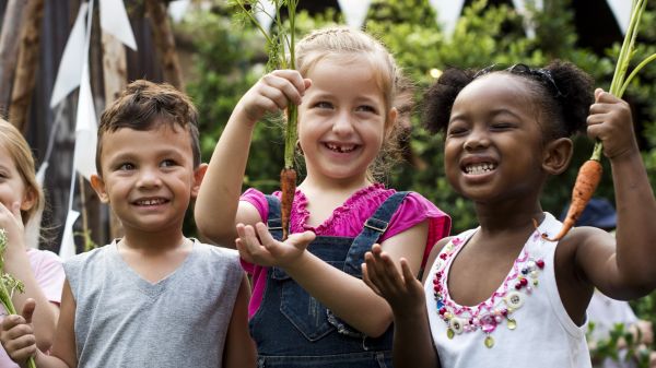 Group of kids holding carrots and on a field trip