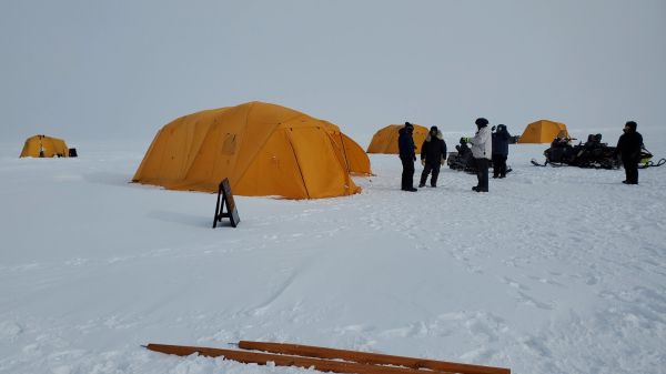 A field research camp with orange arctic tents on snow in Utqiagvik, Alaska.