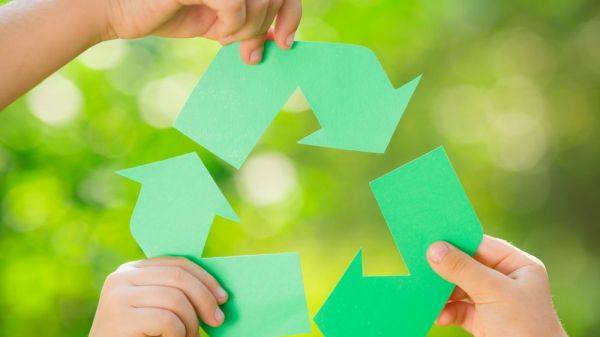 Three hands holding sections of the recycle symbol.