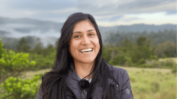 Photo of Blanca Hernández smiling outside in a verdant hilly area