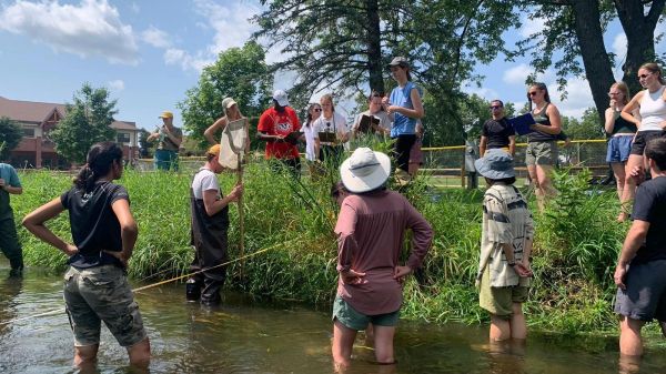 MS engaging in students field. Students standing in bank water and shore.