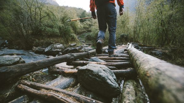 A hiker walking across a wooden bridge