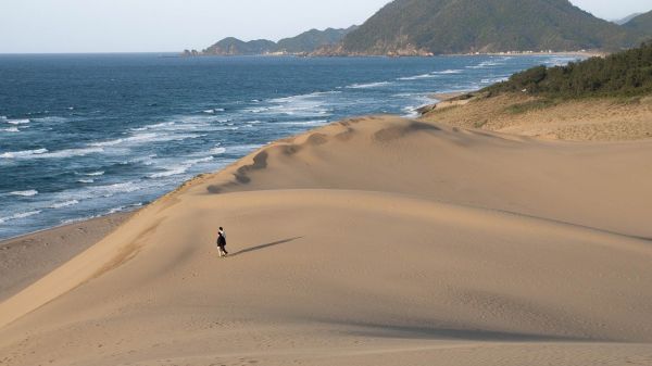 sand dunes near water and a hill