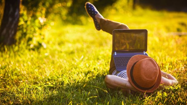 Person lying down on grass With laptop. 