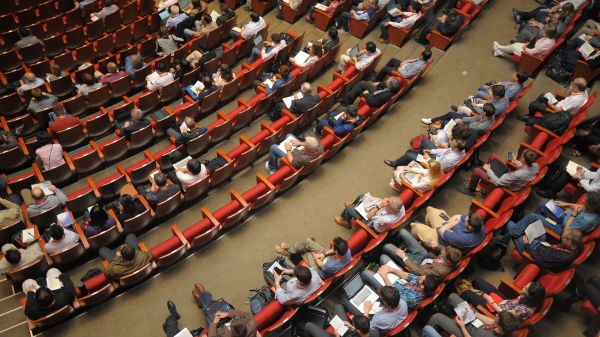 Aerial photo of an event auditorium showing people seated in red chairs