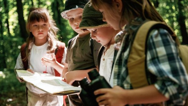 Four young kids in forest looking at map.
