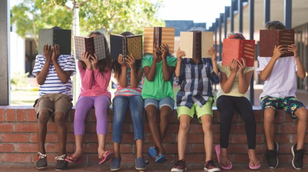 Students sitting and covering faces with books.