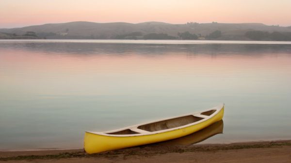 Yellow canoe on the shore of Tomales Bay at dusk with pastel colors and glassy water