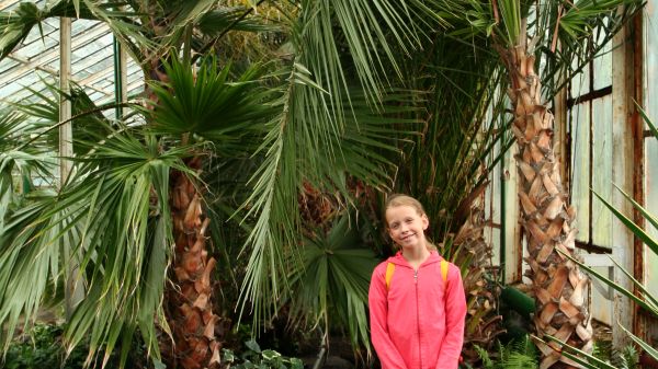 young student standing in greenhouse