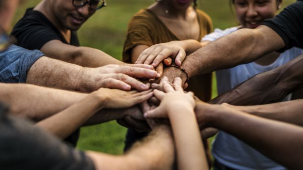 group of people in circle with hands in center