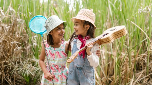 Two girls looking at each other in front of tall grass
