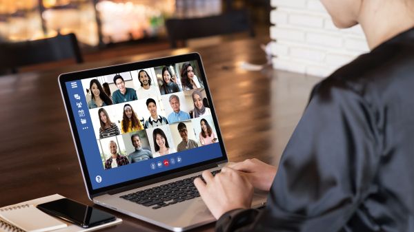 Person using laptop to join a virtual meeting with 15 participants.