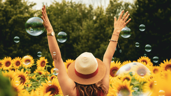 A woman with arms outstretched in a field of sunflowers