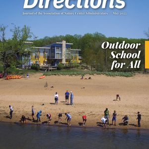 A magazine cover: the top reads in large text, "Directions." A photo of a group of people on a beach, lined up along the water. In the background, a building stands among trees, and a blue sky is above.