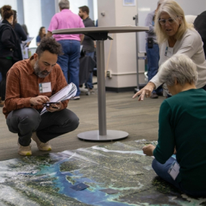 Four Earth to Sky participants take notes and point at a large Landsat map on the ground.