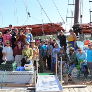 A group of teachers smile while sitting on the deck of a tallship schooner.