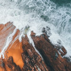 Aerial photo of a beach with ocean waves crashing on rock