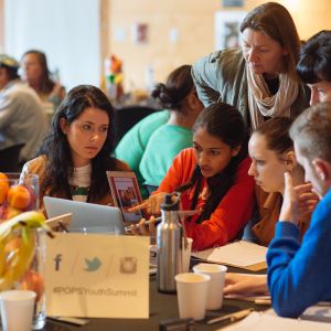 Students with a teacher talking about a lesson plan on a laptop