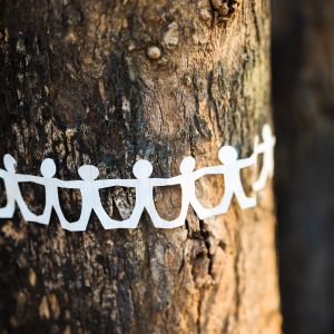 A paper chain with human silhouettes wrapped around a tree trunk