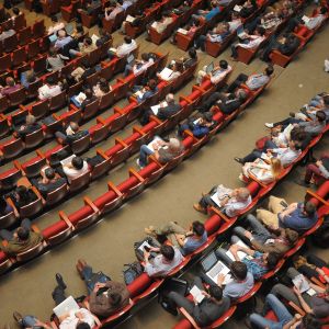 Aerial photo of an event auditorium showing people seated in red chairs