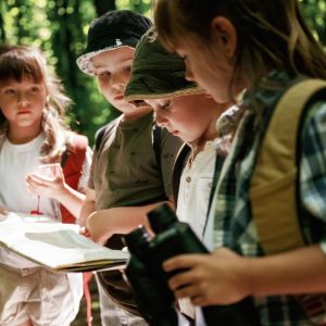 Four young kids in forest looking at map.