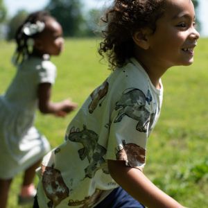 Two kids running outside on grass