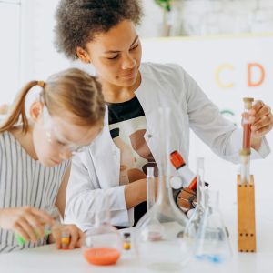 A child and adult stand behind a table full of test tubes and beakers
