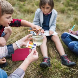 Group of school children with teacher on field trip in nature, learning science.