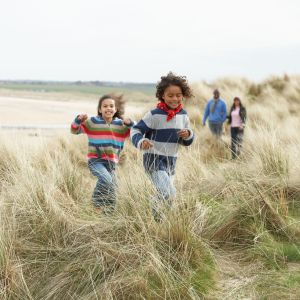 Two young kids and two adults walk along path in high grass.