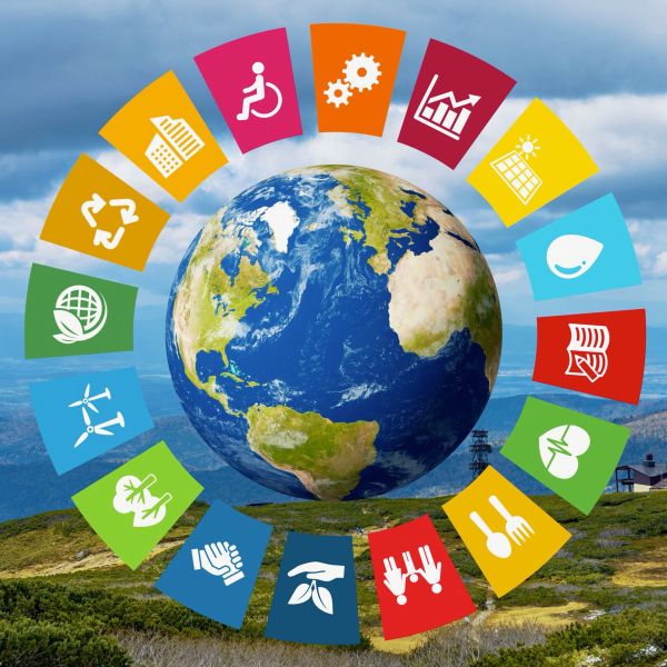 Sustainable development goals icons ringed around the globe. In the background is a photo of a mountian range