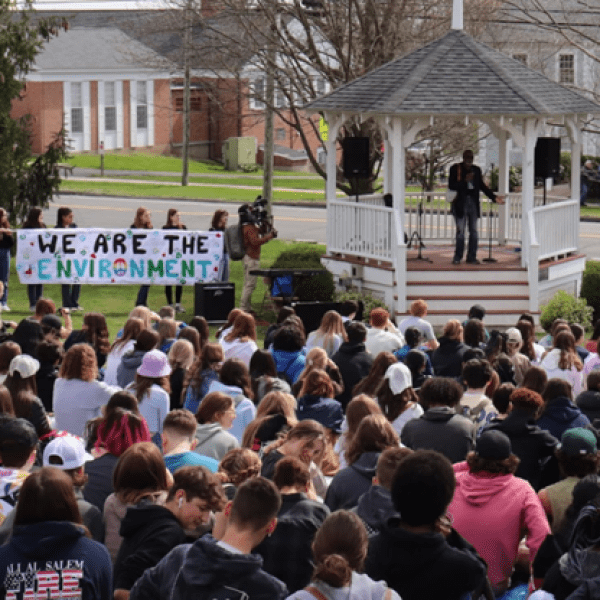 a group of people gathered in front of a speaker and a sign that reads We Are The Environment