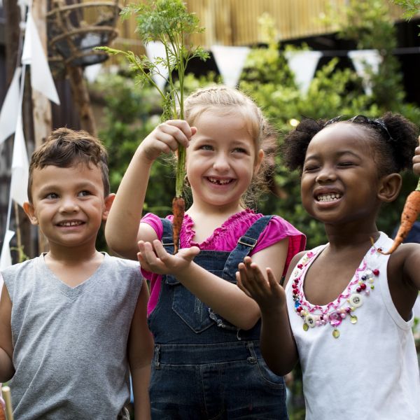 Group of kids holding carrots and on a field trip