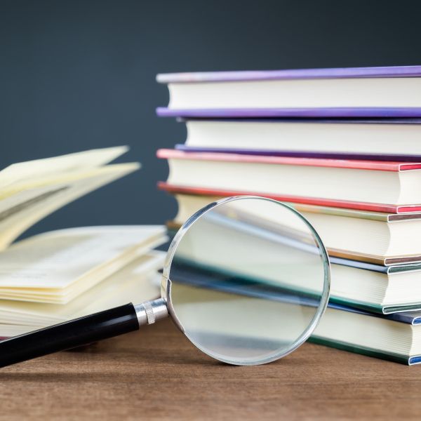 Stack of journals and a magnifying glass on a wooden table