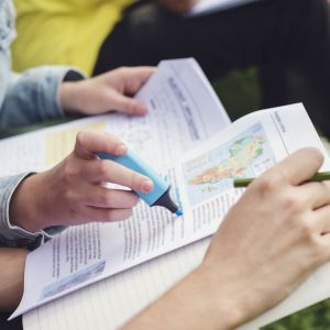 People highlighting books outside